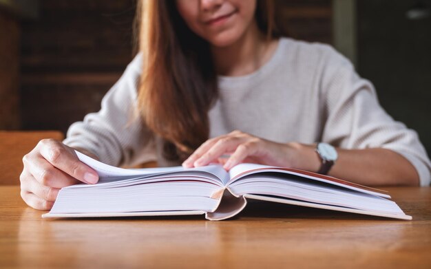 Closeup image of a young woman sitting and reading book at home