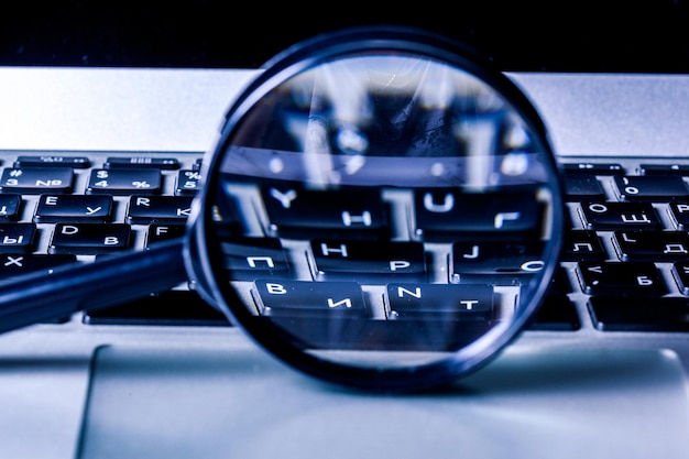 Photo closeup images of magnifying glass on laptop keyboard