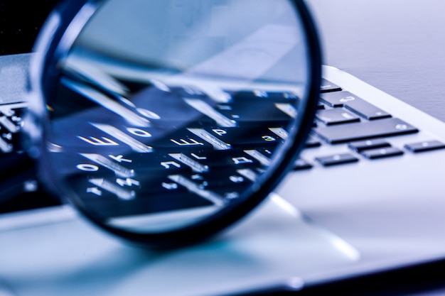 Photo closeup images of magnifying glass on laptop keyboard