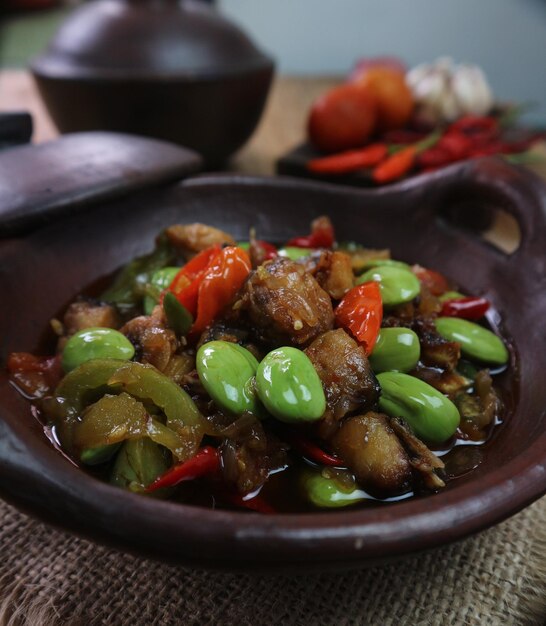 Foto un primo piano di stirfry petai fatto in casa piccante indonesiano servito in un wok di argilla