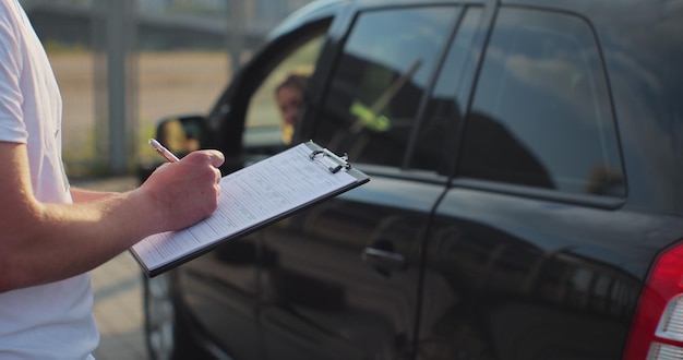 Photo closeup of instructor in driving school writing down results of exam driver courses exam and people concept