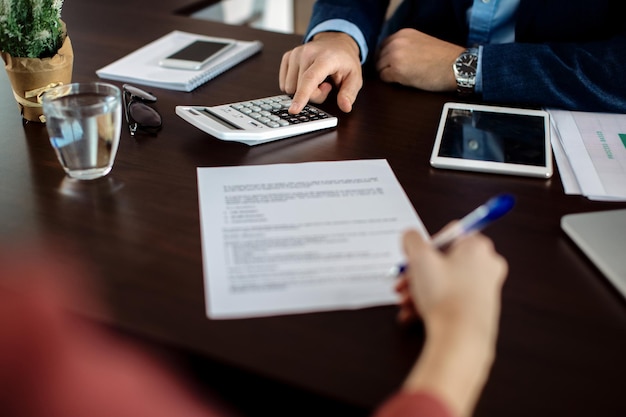 Closeup of insurance agent calculating costs an agreement while having a meeting with a client