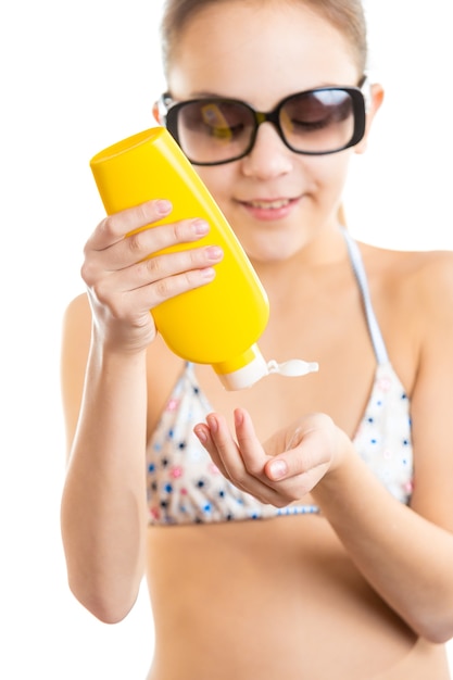 Closeup isolated portrait of cute girl applying sunscreen