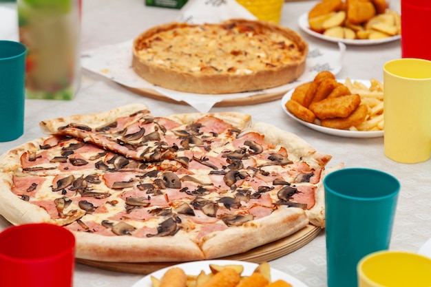 Photo closeup of italian pizza with sausage and mushrooms on the festive table during a party