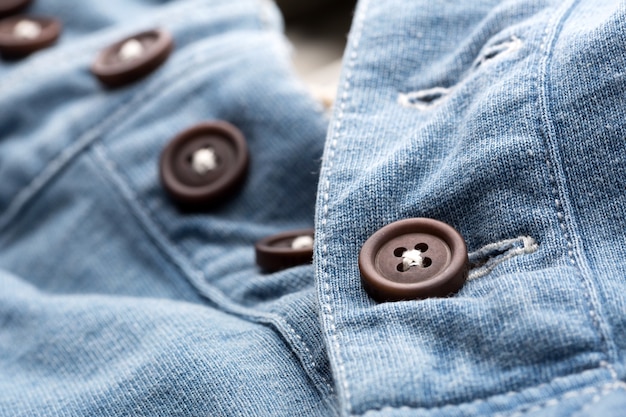 A closeup of jean cardigan with plastic buttons