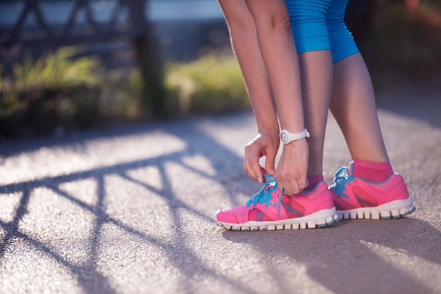 Closeup of jogging woman tying running shoe