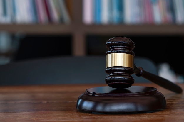 Closeup Judge's gavel on wooden table in dark room with blurred background. Law concept.