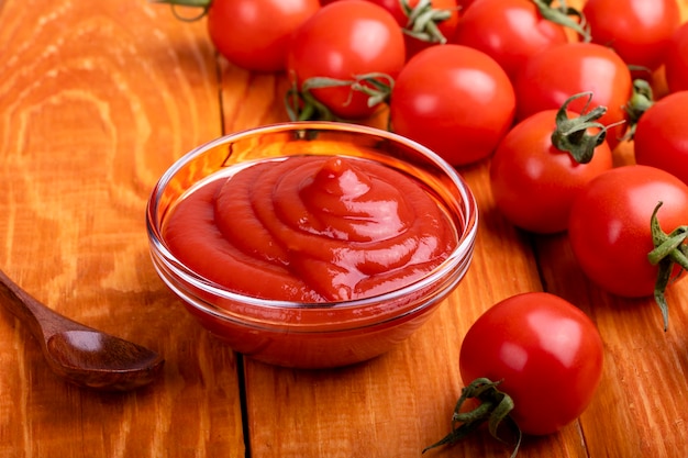 Closeup of ketchup and tomatoes on a wooden background