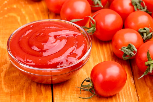 Photo closeup of ketchup and tomatoes on a wooden background