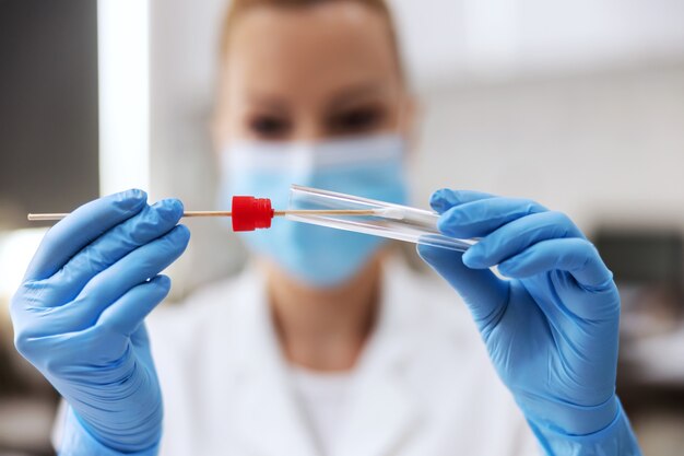 Closeup of lab assistant holding cotton swab after taking a sample from covid positive patient.