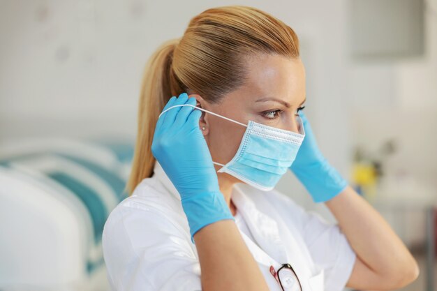 Closeup of lab assistant putting protective mask on face