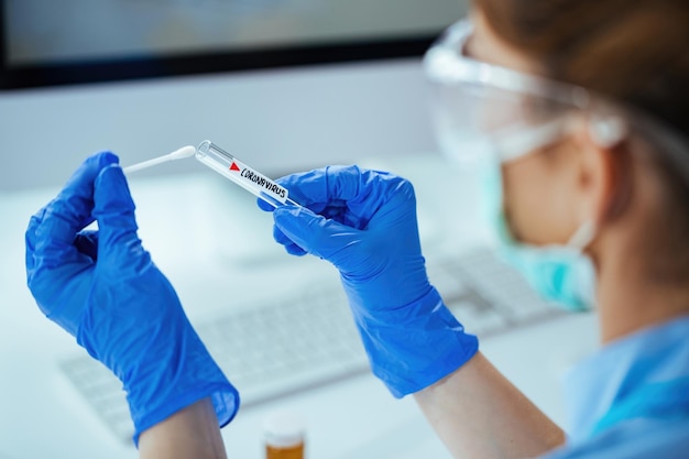 Primo piano del tecnico di laboratorio che esamina il campione di coronavirus mentre lavora nel laboratorio di prova