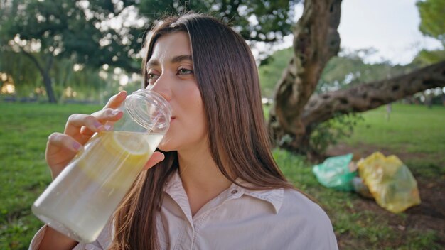 Foto una signora in primo piano che sorseggia una bevanda nel parco una donna felice che stende la sete bevendo