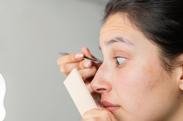 Closeup of a latina woman's face looking closely in the mirror to make up her eyes