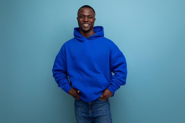 Closeup of a laughing black american man in a sweatshirt with a hood on a studio background with