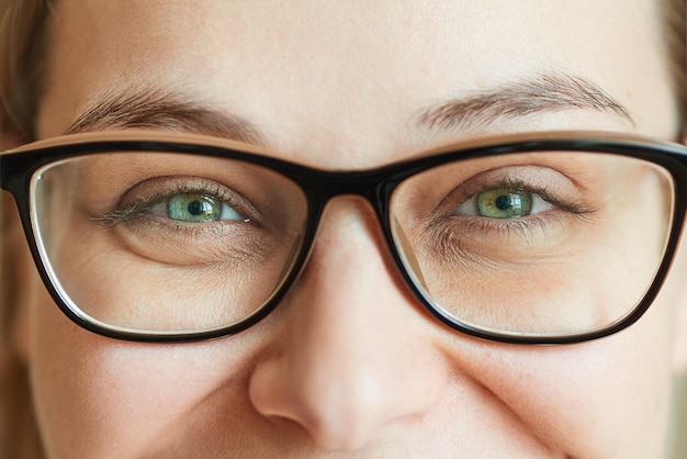 Closeup laughing eyes of a young beautiful woman in glasses