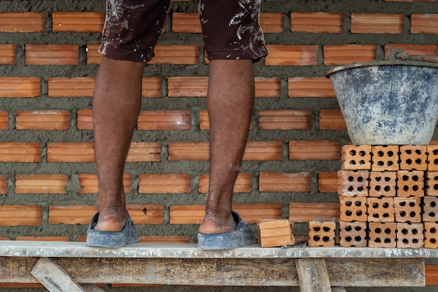 Closeup leg of professional construction worker laying bricks in new industrial site