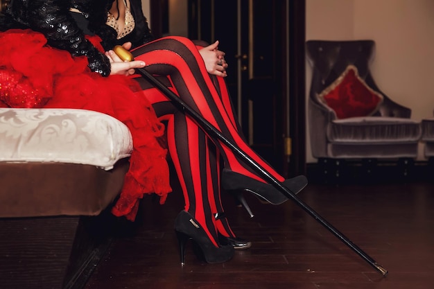 Closeup of legs of circus performer in suit and striped redblack stockings in dressing room