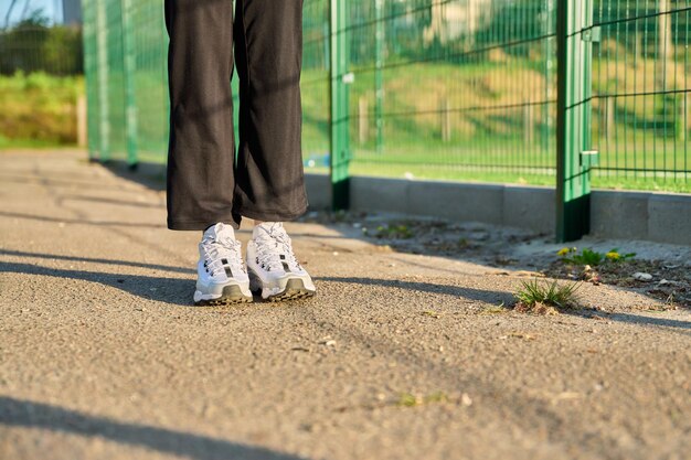 Closeup of legs in white sneakers at the stadium copy space road