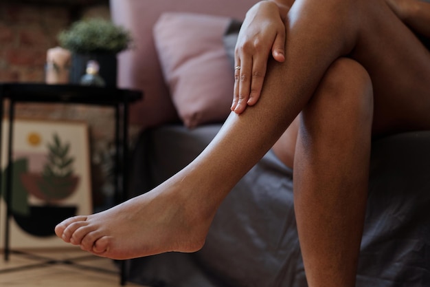 Closeup of legs of young woman touching her smooth skin