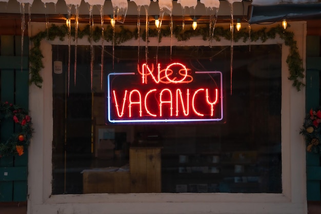 Closeup of the lighted signage saying "NO VACANCY" on the glass window