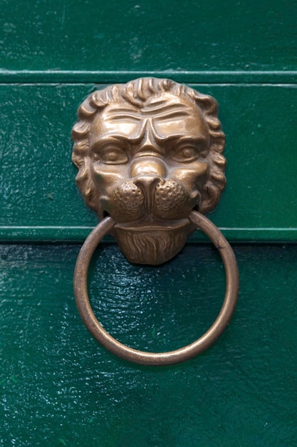 Closeup on a lion head door knocker on a green door in Napoli Italy