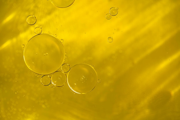 Photo closeup of liquid golden oil serum with bubbles as texture or background