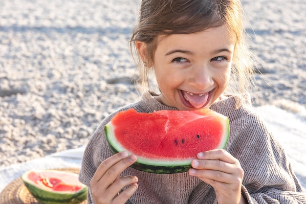 Photo closeup little girl eats watermelon on the beach