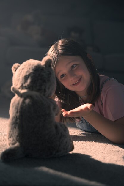 Photo closeup of little girl talking with teddy bear