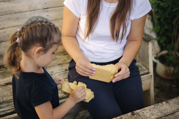 Photo closeup of little girl with her mom preparing cardboard for recycling family sorting garbage at home