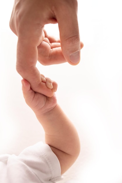 Photo closeup little hand of child and palm of mother and father the newborn baby has a firm grip on the parent39s finger after birth a newborn holds on to mom39s dad39s finger