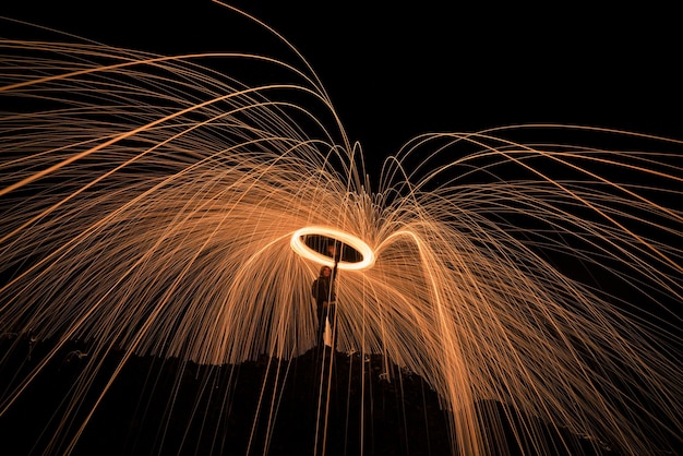 Closeup of long exposure of sparks from a male performer against a dark night