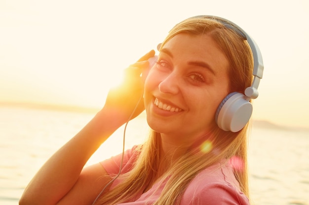 Closeup lovely woman in sunset light glare on her face enjoying music in headphones