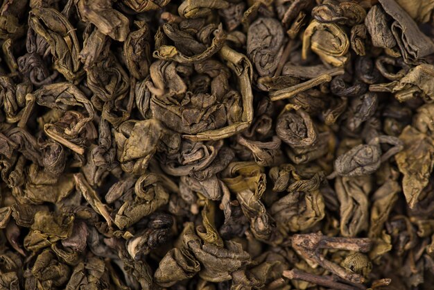 Closeup macro photo of dry loose green herbal tea leaves textured background