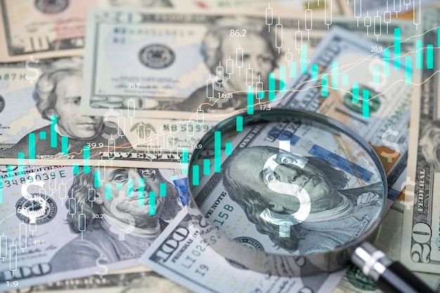 Photo closeup on magnifier glass with benjamin franklin on us dollar banknote and stock market graph for currency exchange and interest rates concept