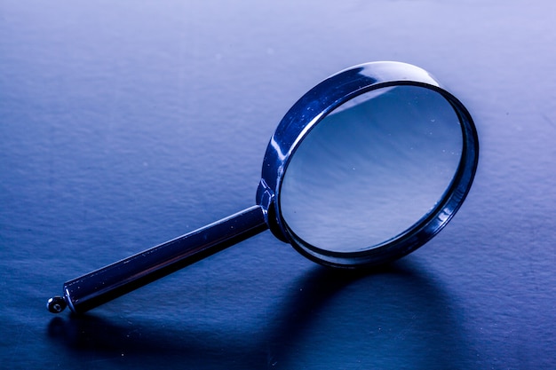 Photo closeup of magnifying glass on dark surface