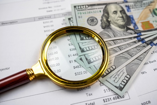 Closeup of Magnifying glass dollar and pen on business charts graphs paper