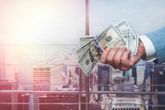 Closeup male agent in suit hold dollar bills in hand to pay expenses or shopping