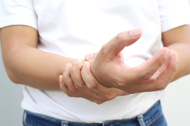 closeup of male arms holding his painful wrist caused by prolonged work office syndrome rheumatoid arthritis gout or sprain weakness and tingling health care concept