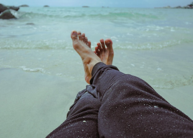 Крупным планом мужские ноги на пляже путешествия туризм отдых люди и концепция летних каникул