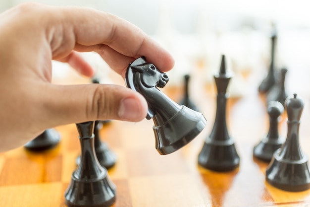 Closeup male hand holding black horse chess piece