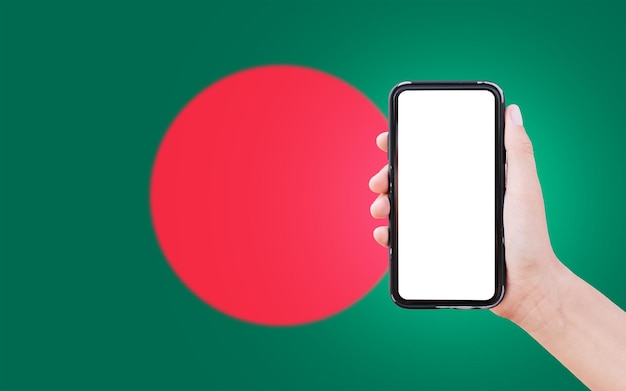 Closeup of male hand holding smartphone with blank on screen on background of blurred flag of Bangladesh