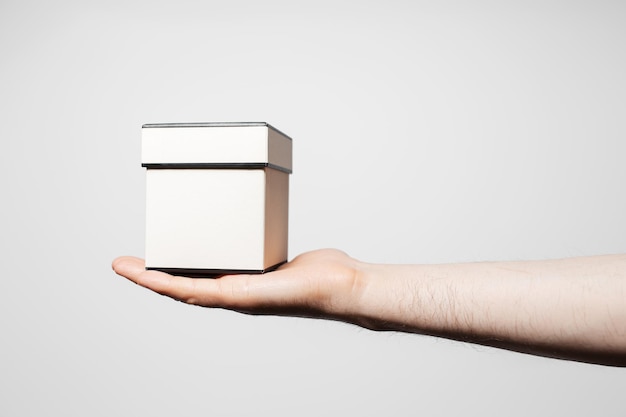 Closeup of male hand showing a small box on white background