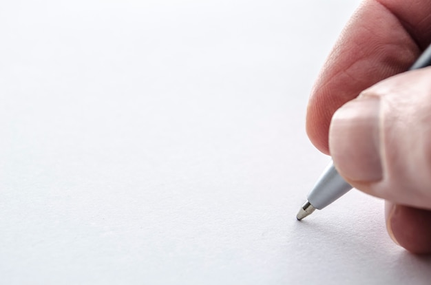 Closeup of a male hand writing on a blank paper.