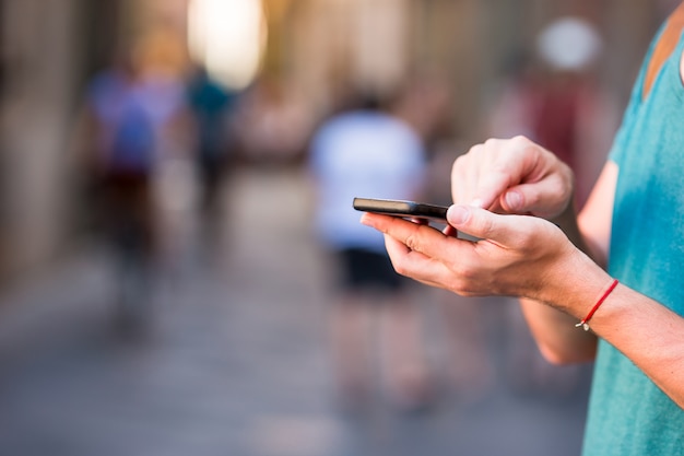 Il primo piano delle mani maschii sta tenendo il cellulare all'aperto sulla via. uomo che usando smartphone mobile.