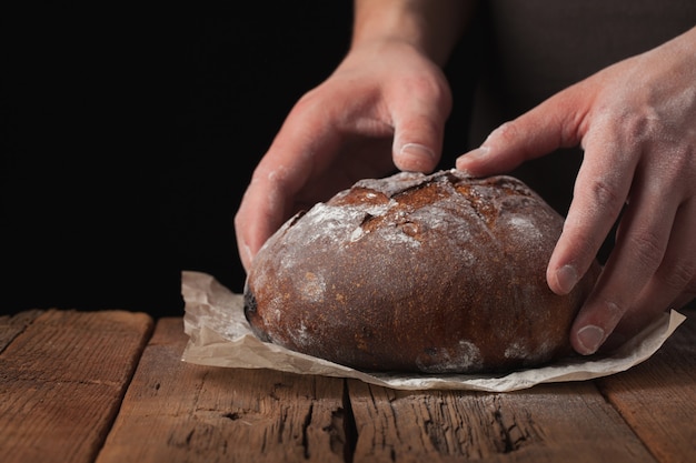 Closeup of male hands put fresh bread.