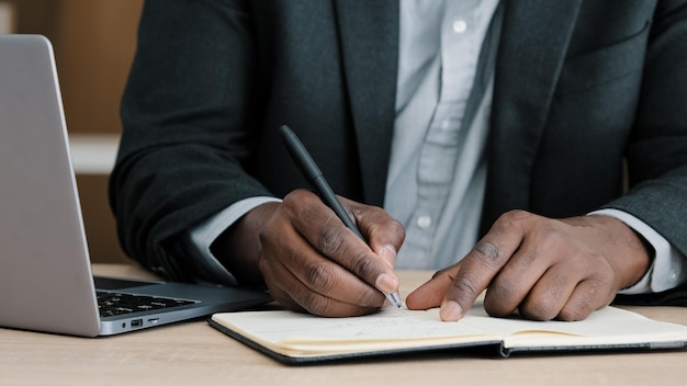 Closeup male hands writing in notebook with pen make notes information financial analysis startup