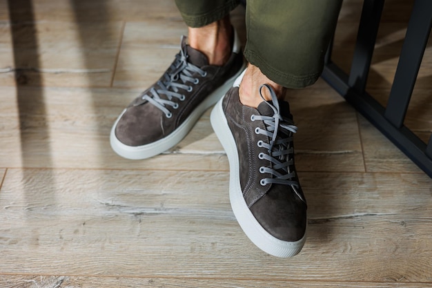 Closeup of male legs in pants and gray casual sneakers Men's leather shoes Collection of men's stylish summer shoes