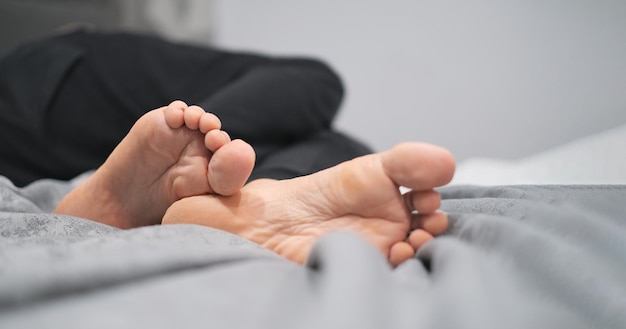 Closeup of male legs with feet forward lying on the bed while resting vacation concept