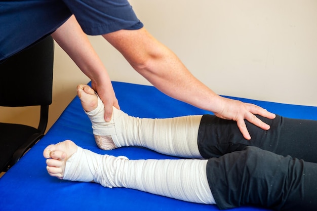 Photo closeup of male physiotherapist massaging the leg of patient in a physio room